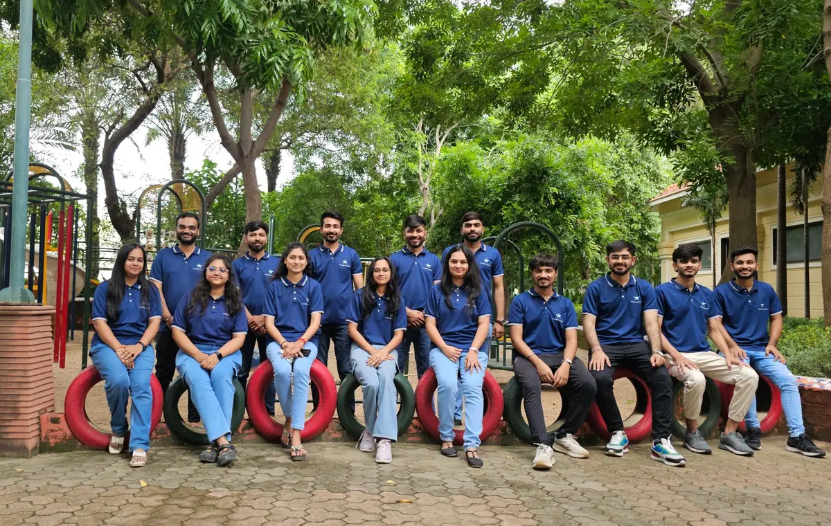 The TeqStars team in company polo shirts outdoors, one row seated on painted tyres and one row standing behind