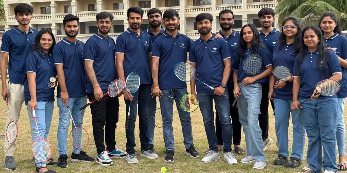The TeqStars team in company polo shirts on a lawn, holding badminton rackets
