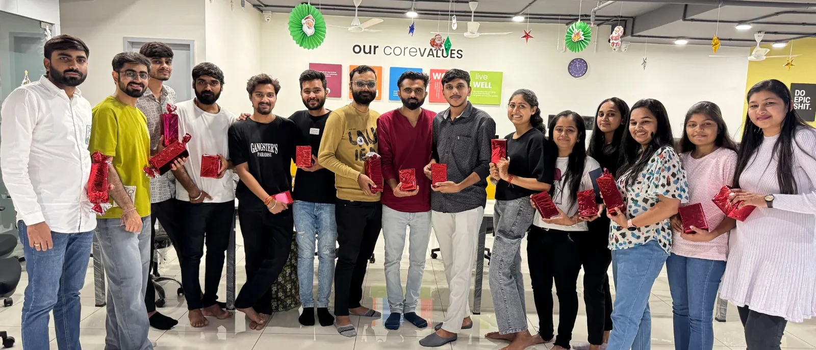 TeqStars team members holding red-wrapped Christmas gifts in the office